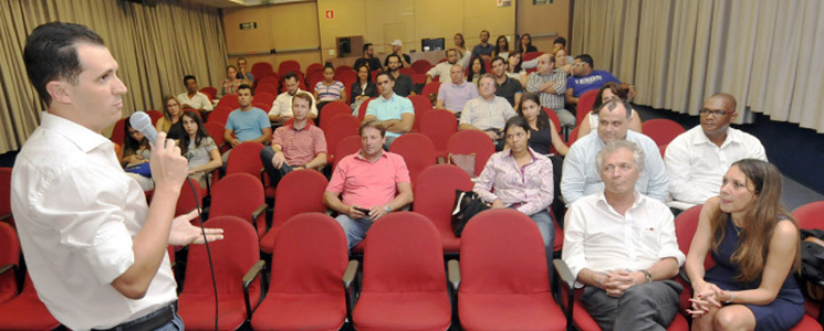 Palestrante em pé fala em frente à pessoas sentadas no auditório da unidade Palestrante em pé fala em frente à pessoas sentadas no auditório da unidade