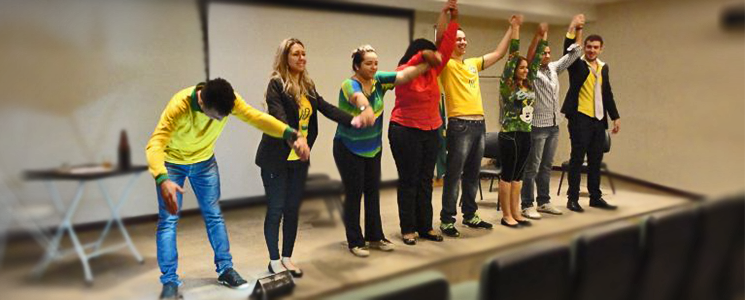 Alunos no palco de auditório com as mãos dadas levantadas Alunos no palco de auditório com as mãos dadas levantadas