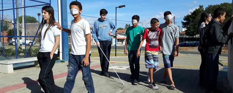 Adolescentes caminham pelo ambiente vendados. Adolescentes caminham pelo ambiente vendados.