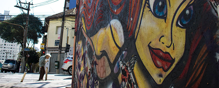Imagem de idosa caminhando ao lado de muro grafitado Imagem de idosa caminhando ao lado de muro grafitado