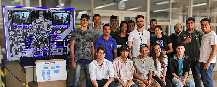Turma posa ao lado do sistema desenvolvido no curso Turma posa ao lado do sistema desenvolvido no curso