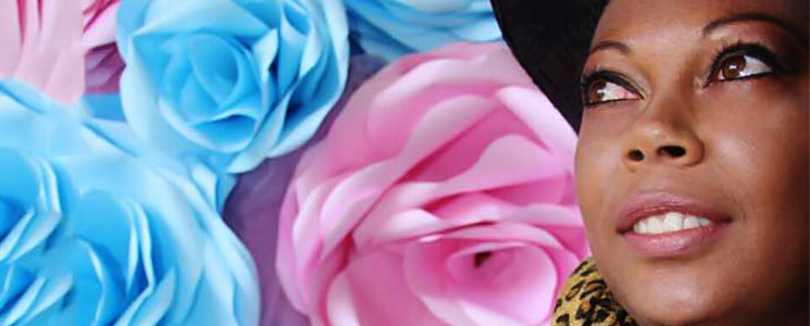 Mulher à direita com maquiagem leve olhando para a direita em frente a fundo com imagem de rosas Mulher à direita com maquiagem leve olhando para a direita em frente a fundo com imagem de rosas