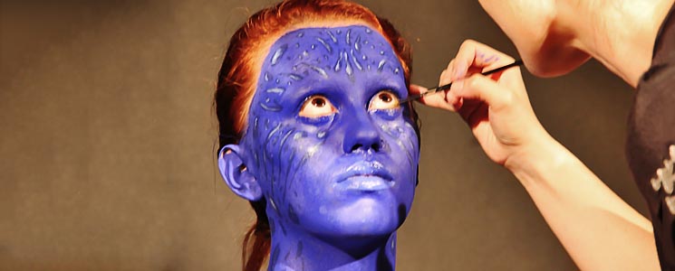 Docente finalizando maquiagem do olho de modelo com pintura azul Docente finalizando maquiagem do olho de modelo com pintura azul