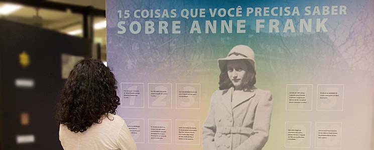 Visitante observa painel com informações e foto de Anne Frank Visitante observa painel com informações e foto de Anne Frank