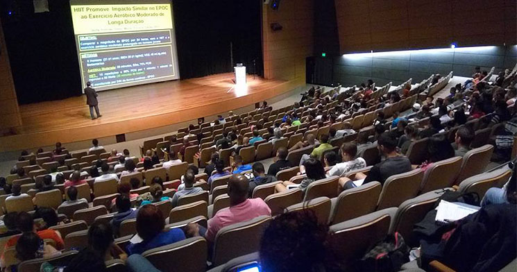 Palestrante se apresenta no palco do auditório do evento Palestrante se apresenta no palco do auditório do evento