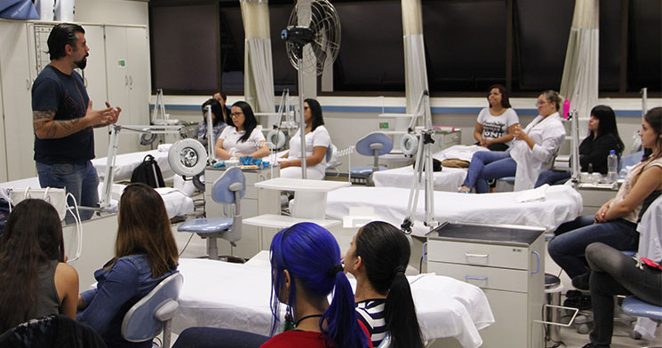 Alunas sentadas no laboratório de estética do Senac Tatuapé ouvem orientações do docente Milton Mansilha sobre fotografia com celular antes da atividade Alunas sentadas no laboratório de estética do Senac Tatuapé ouvem orientações do docente Milton Mansilha sobre fotografia com celular antes da atividade