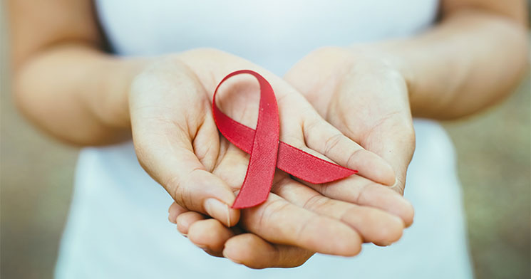 Mãos em concha com uma fita vermelha enlaçada reproduzindo o símbolo de atenção à prevenção da Aids Mãos em concha com uma fita vermelha enlaçada reproduzindo o símbolo de atenção à prevenção da Aids