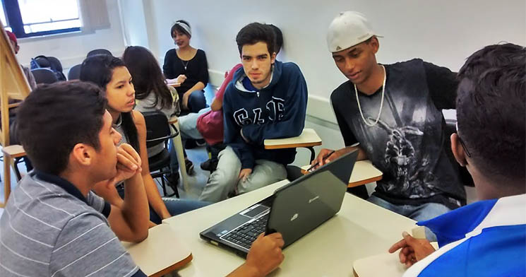 Jovens alunos do programa Aprendizagem do Senac Jabaquara reunidos em volta de um computador móvel Jovens alunos do programa Aprendizagem do Senac Jabaquara reunidos em volta de um computador móvel