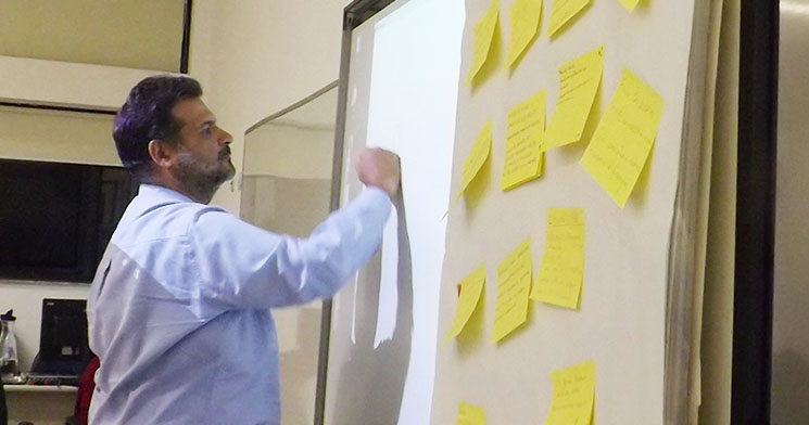 Homem escreve em lousa com post-its Homem escreve em lousa com post-its