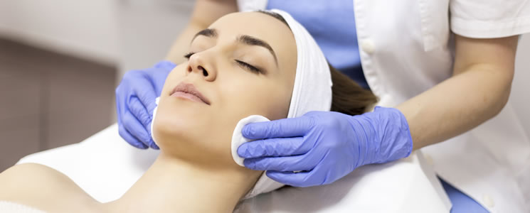 profissional, com luvas azuis, limpa a pele da paciente com algodão profissional, com luvas azuis, limpa a pele da paciente com algodão