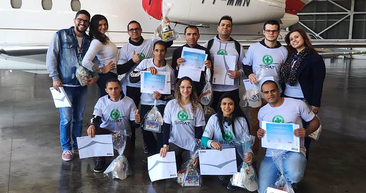 Alunos do curso Técnico em Segurança do Trabalho do Senac Jabaquara enfileirados e sorridentes com camisetas escritas SIPAT segurando certificados em frente a uma aeronave da TAM Aviação Executiva Alunos do curso Técnico em Segurança do Trabalho do Senac Jabaquara enfileirados e sorridentes com camisetas escritas SIPAT segurando certificados em frente a uma aeronave da TAM Aviação Executiva