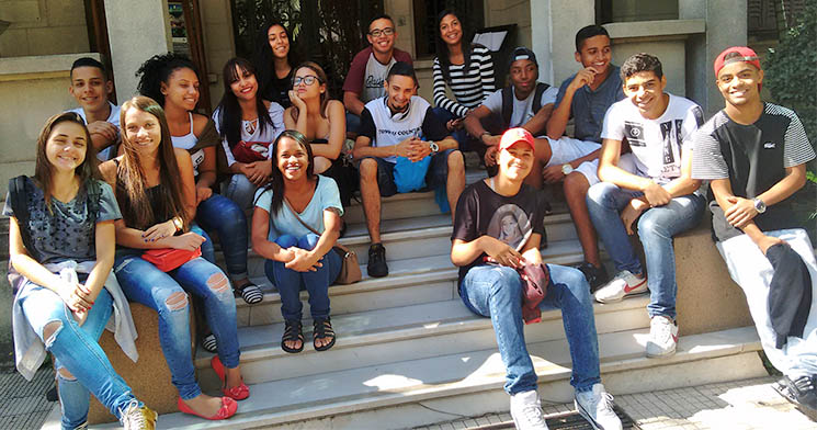 Alunos do programa Aprendizagem do Senac Jardim Primavera sentados em fila, sorridentes Alunos do programa Aprendizagem do Senac Jardim Primavera sentados em fila, sorridentes
