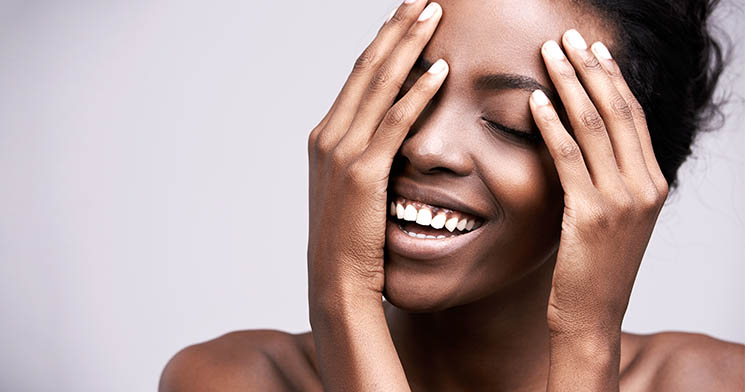 Mulher negra sorrindo com as mãos no rosto Mulher negra sorrindo com as mãos no rosto