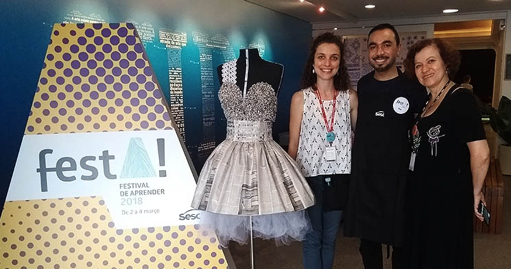Ricardo e duas mulheres ao lado de busto com peça de moulage e de banner do evento FestA Ricardo e duas mulheres ao lado de busto com peça de moulage e de banner do evento FestA