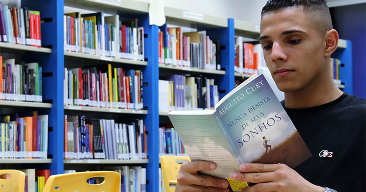 Aluno Marcio lê o livro Nunca Desista de seus Sonhos, de Augusto Cury, sentado na biblioteca da unidade Aluno Marcio lê o livro Nunca Desista de seus Sonhos, de Augusto Cury, sentado na biblioteca da unidade