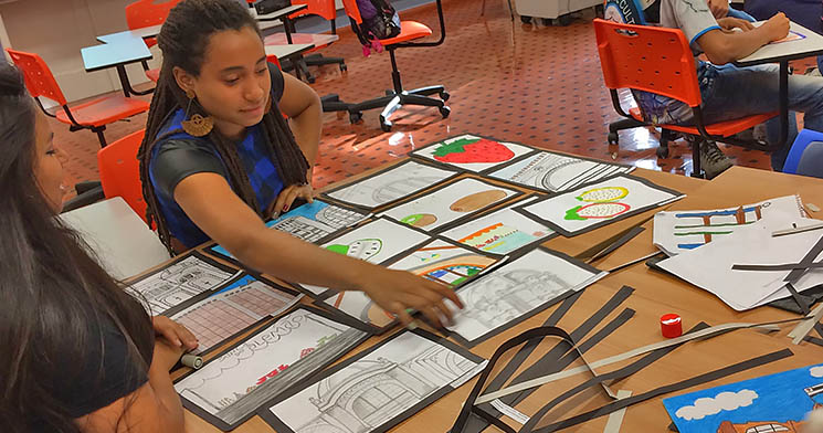Jovem aponta para desenhos sobre a mesa Jovem aponta para desenhos sobre a mesa