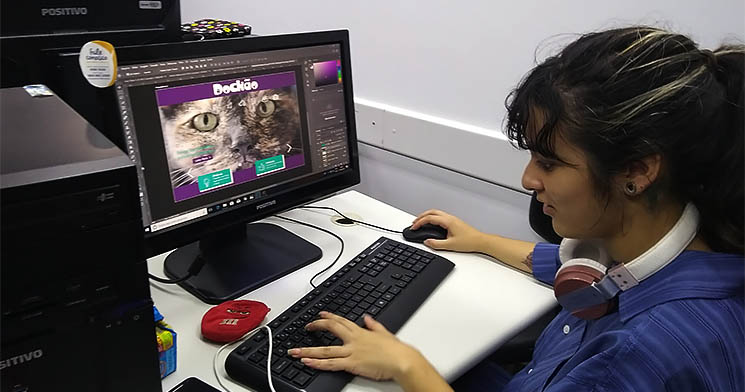 Menina com fone de ouvido ao redor do pescoço mexe em computador Menina com fone de ouvido ao redor do pescoço mexe em computador
