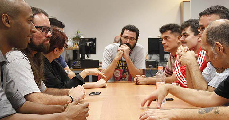 Homens conversam reunidos ao redor de mesa Homens conversam reunidos ao redor de mesa