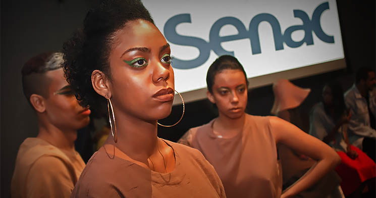 Três modelos maquiados com roupas marrons nos bastidores do evento Três modelos maquiados com roupas marrons nos bastidores do evento