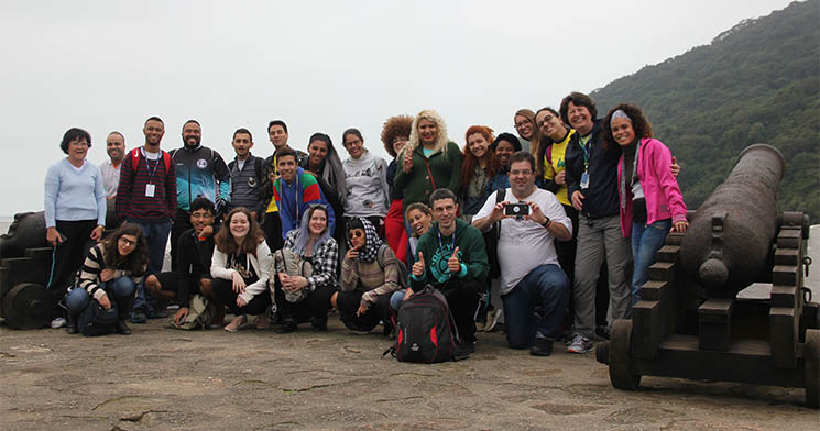 Alunos reunidos ao lado de canhão em área verde Alunos reunidos ao lado de canhão em área verde