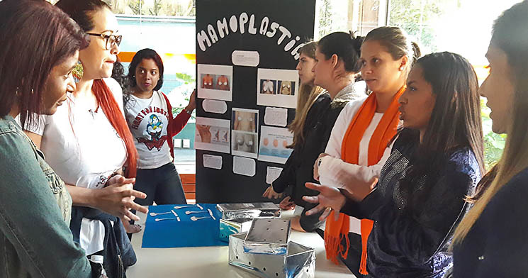 Em bancada, alunas falam com público durante exposição Em bancada, alunas falam com público durante exposição