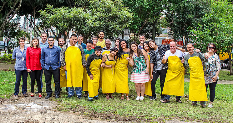 Alunos e docentes posam para foto na praça. Alguns deles vestem aventais amarelos. Alunos e docentes posam para foto na praça. Alguns deles vestem aventais amarelos.