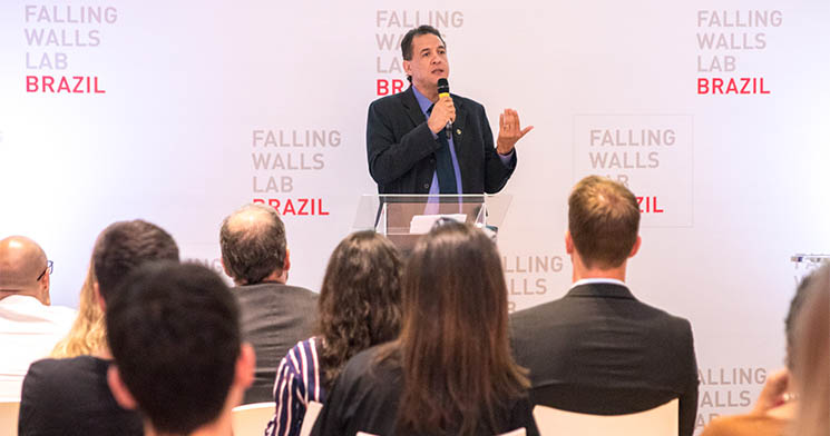 Professor Gustavo Alves Andrade dos Santos apresenta trabalho em frente a painel com o nome do evento Falling Walls Lab Brazil Professor Gustavo Alves Andrade dos Santos apresenta trabalho em frente a painel com o nome do evento Falling Walls Lab Brazil