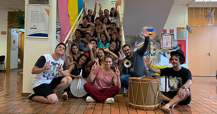 Alunos de teatro com instrumentos musicais sentados em escada do Senac Limeira Alunos de teatro com instrumentos musicais sentados em escada do Senac Limeira