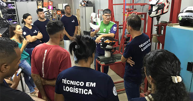 Alunos acompanham fala de profissional de empresa perto de maquinário Alunos acompanham fala de profissional de empresa perto de maquinário