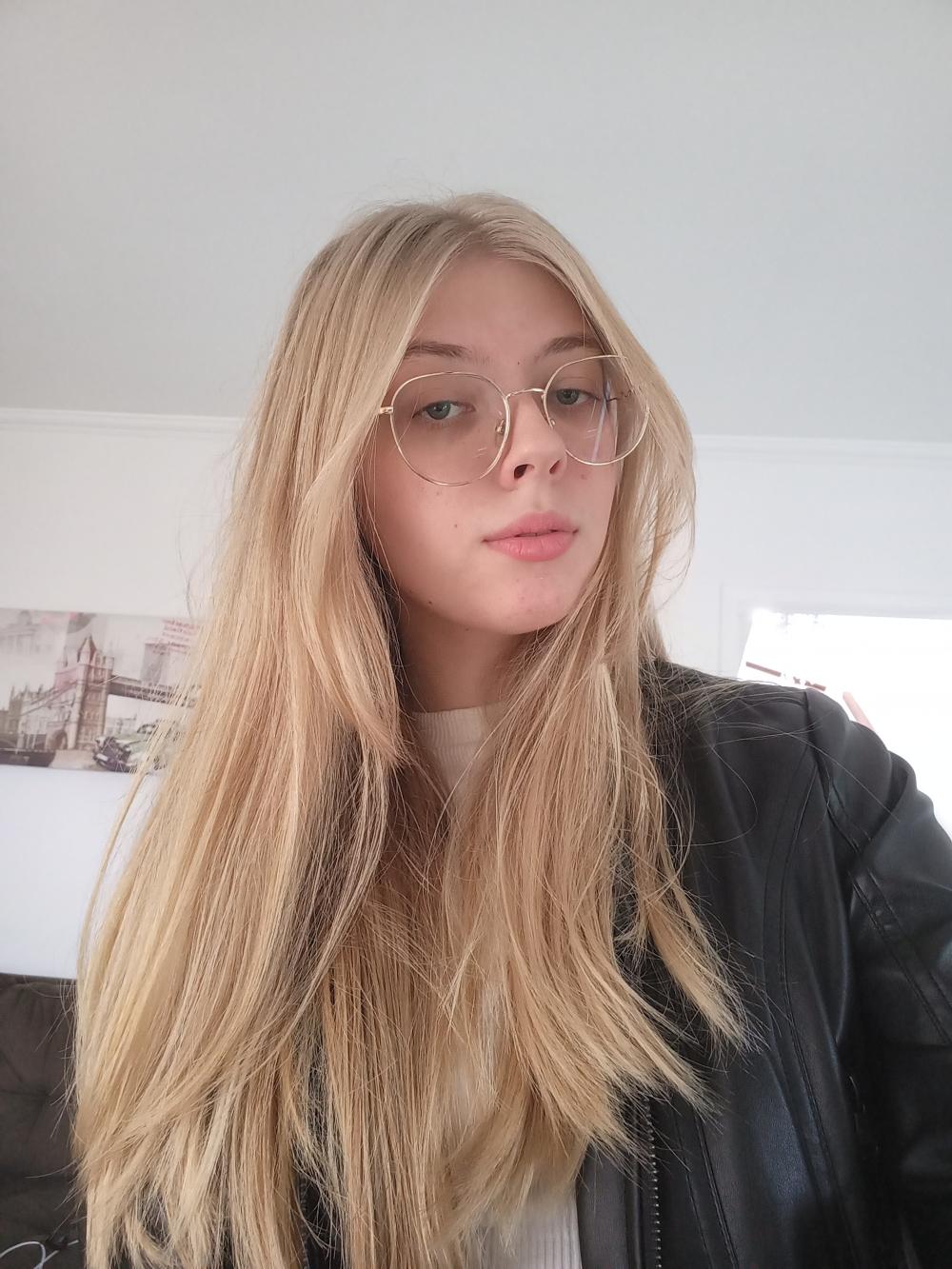 Foto de adolescente loira de cabelos longos e óculos de grau.