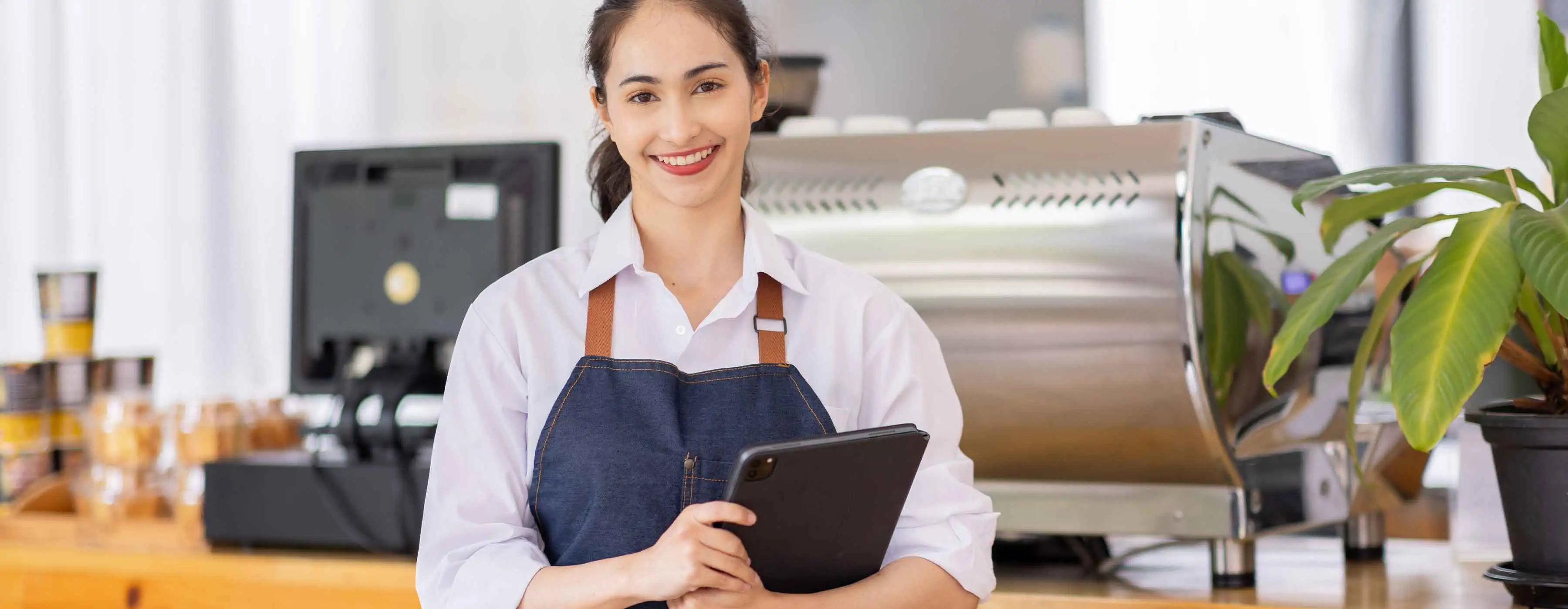 Gestão Financeira para Food Service - Foto de uma mulher com avental de cozinha, segurando um tablet em uma cozinha profissional