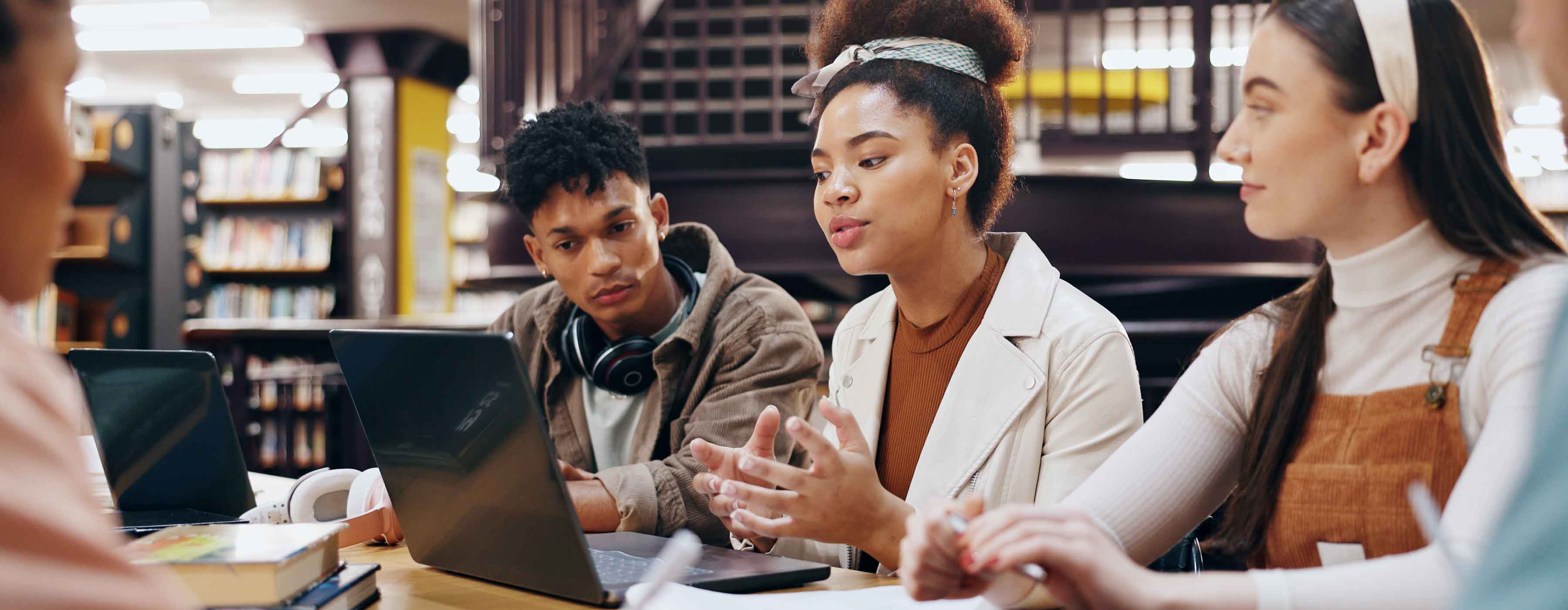Foto de três jovens conversando enquanto olham para o computador.