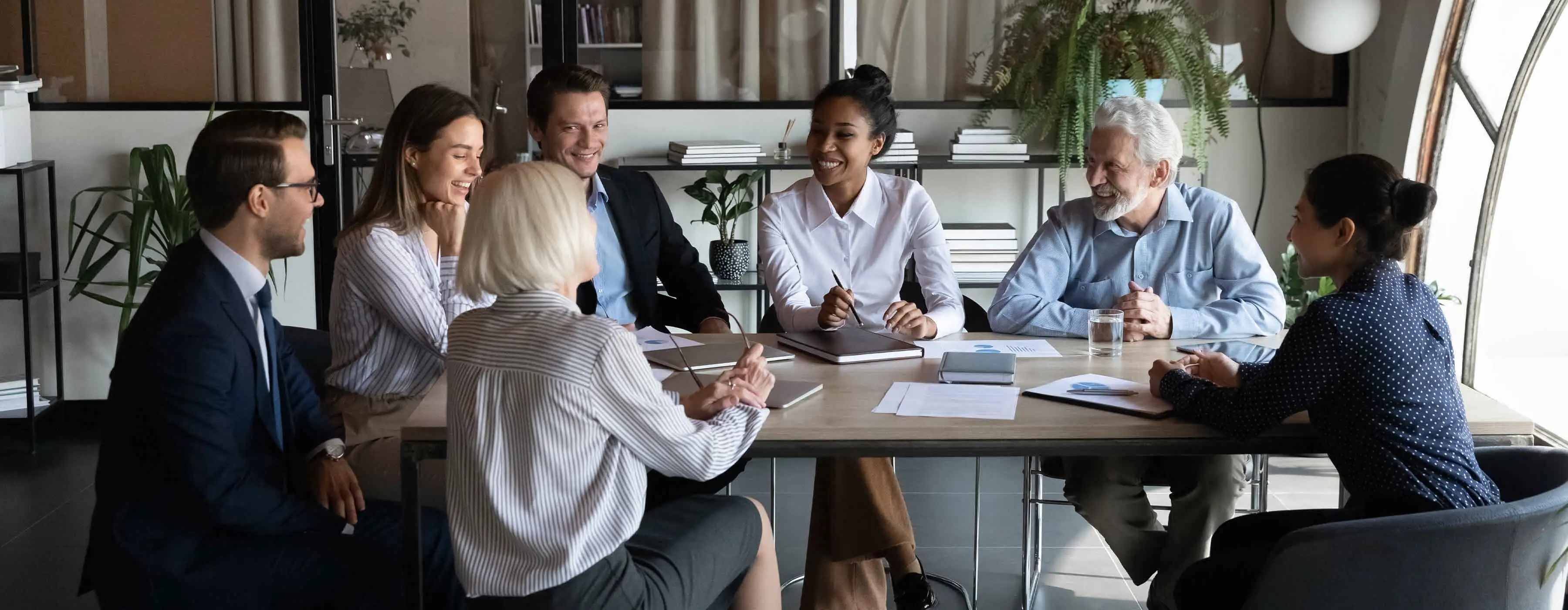 Equipe se reúne em volta de uma mesa em reunião.