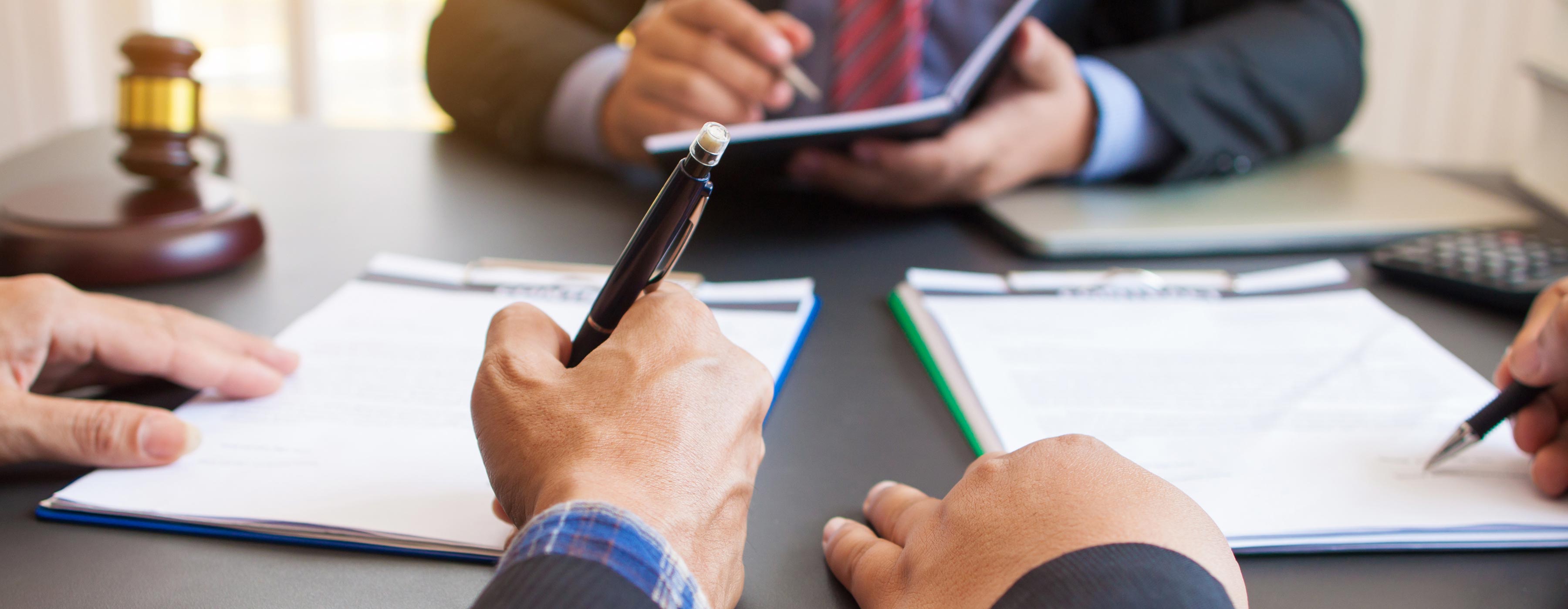 Formação em Conciliação e Mediação de Conflitos nas Relações Sociais e Ambientais. Foto de mãos segurando canetas apoiadas sobre papeis.