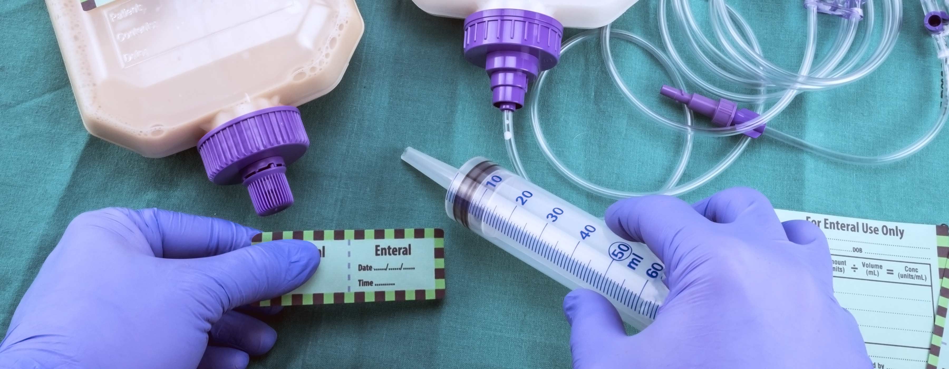 Terapia Nutricional em Paciente Oncológico - Foto em close das mãos de uma pessoa segurando uma seringa para preparar a nutrição de paciente oncológico.