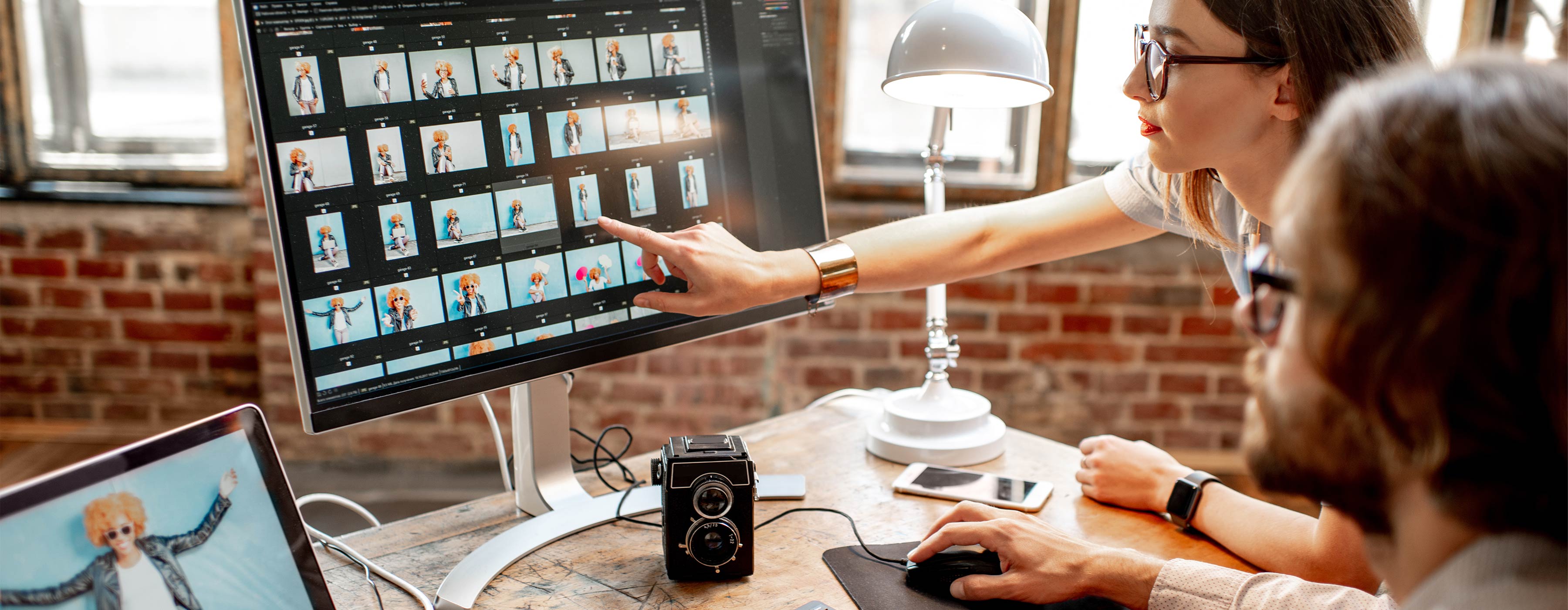 Photoshop e CorelDRAW: tratamento de imagem e ilustração digital - Foto de mulher e homem observando série de imagens de ensaio fotográfico com uma pessoa na tela de computador.