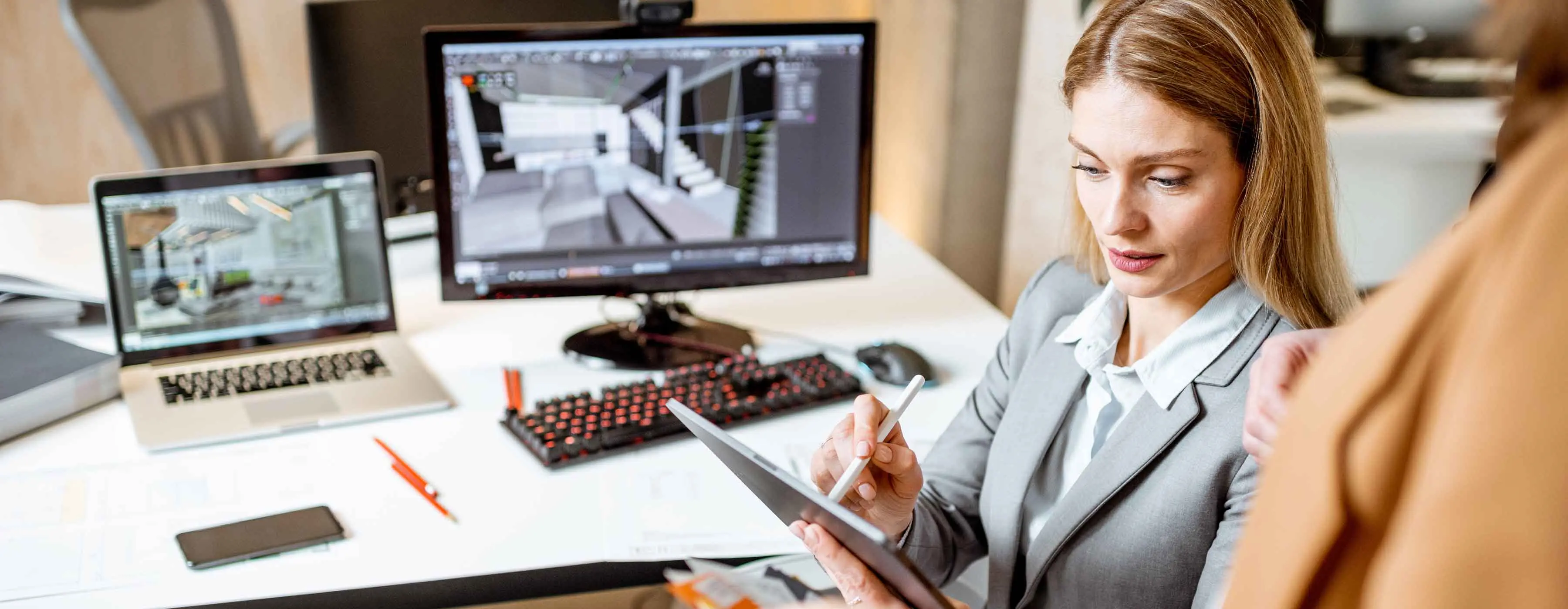 BIM - revit avançado - foto de mulher manuseando tablet com monitor e notebook em uma mesa atrás dela