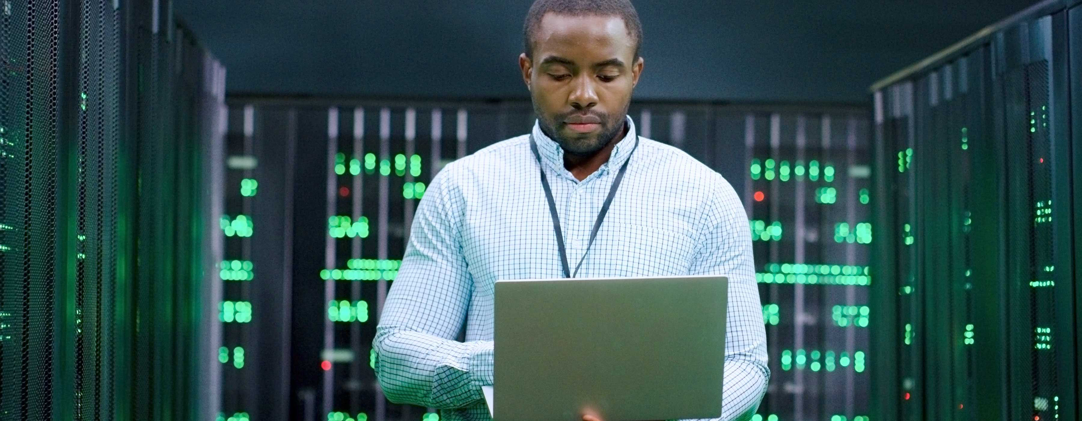 Foto de homem teclando em notebook em espaço de rede se servidores de empresa.