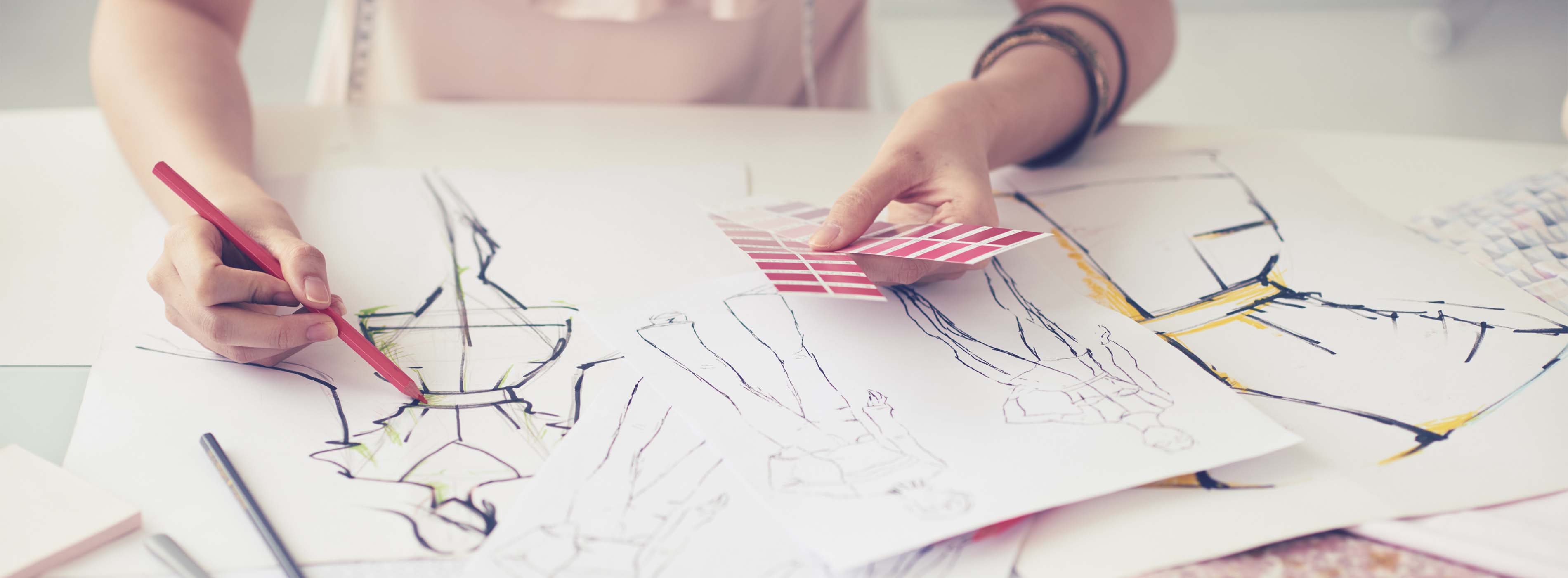 Modelagem e Confecção de Bolsas em Tecido. Foto em close de pessoa desenhando e colorindo croquis de moda.
