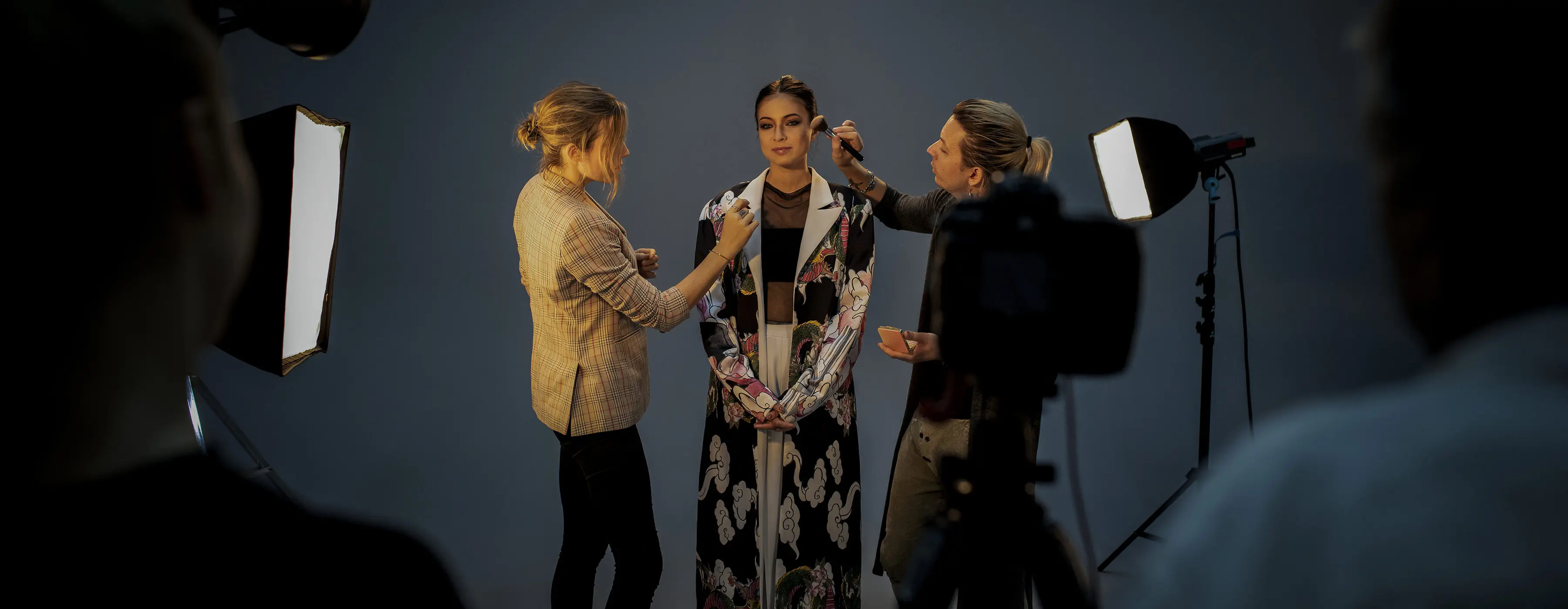 Foto de uma modelo profissional sendo arrumada por figurinista e maquiadora em set de forografia 