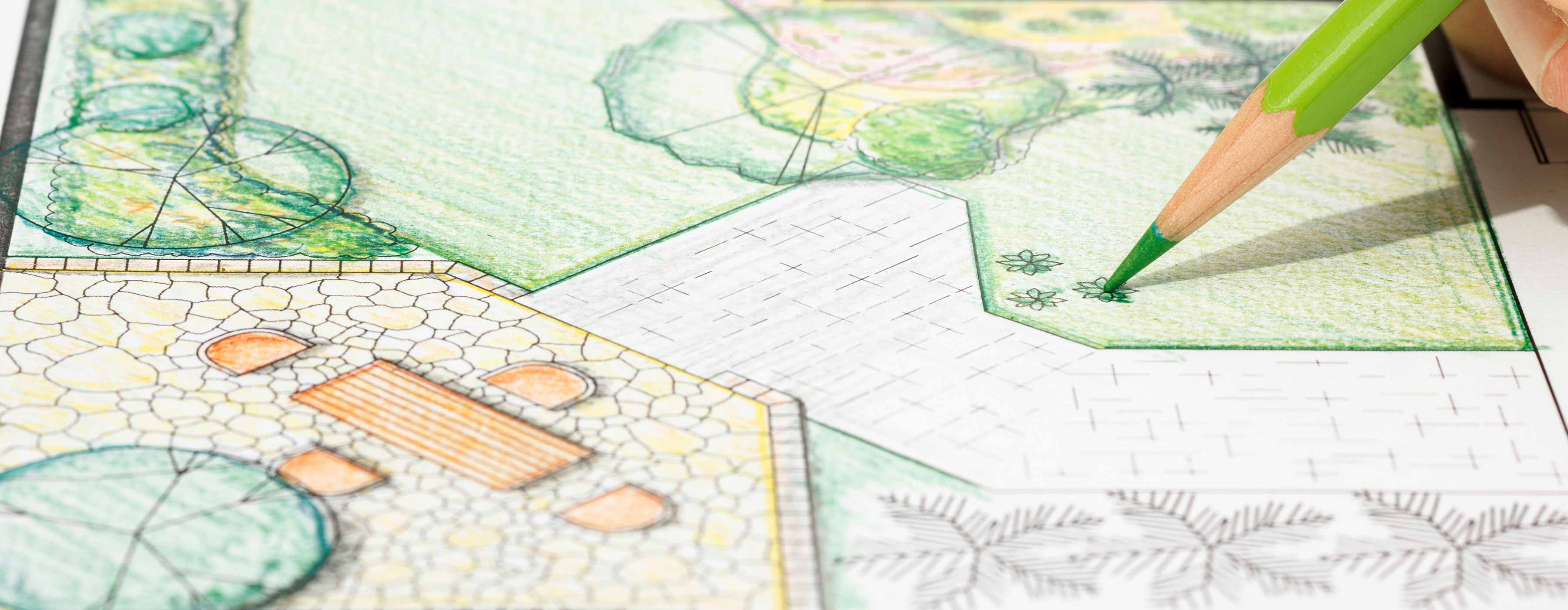 Foto em close de uma maquete de paisagismo, com mão de pessoa colorindo a maquete com lápis de cor