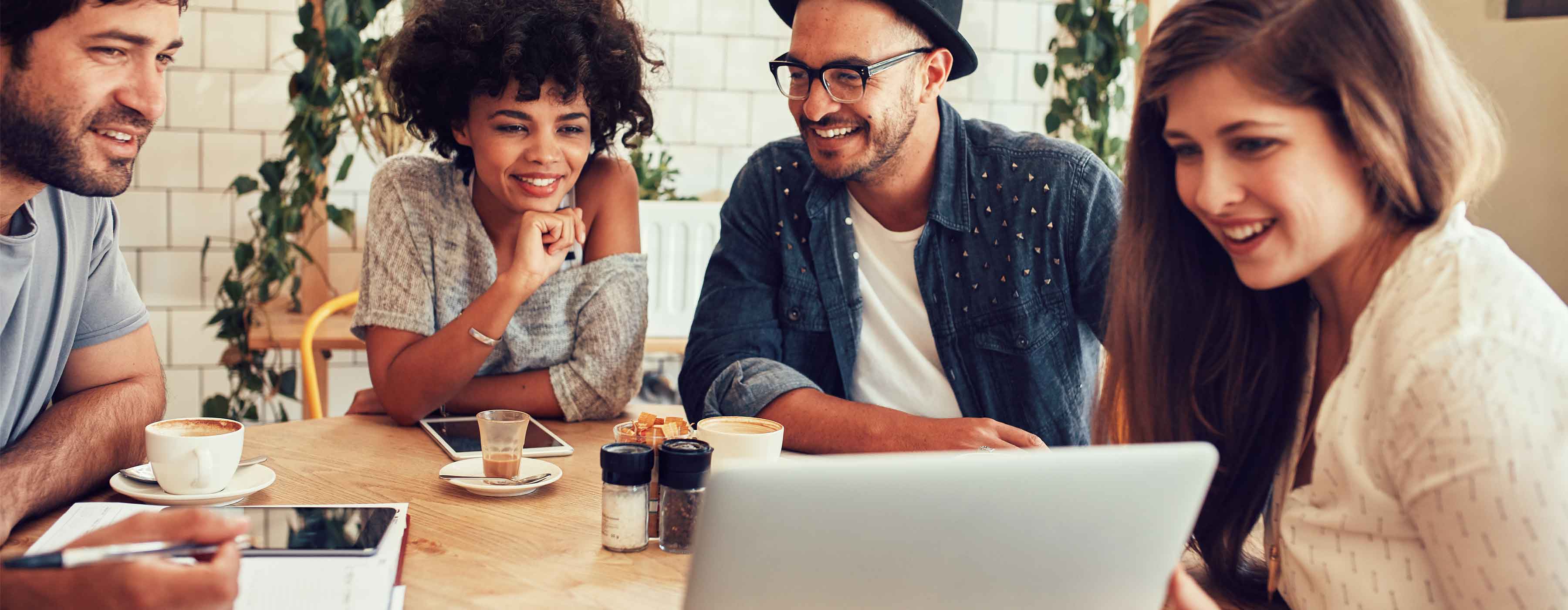 Bares e Restaurantes - gestão de equipes: foto de grupo de pessoas sorrindo olhando para uma tela de computador enquanto tomam café