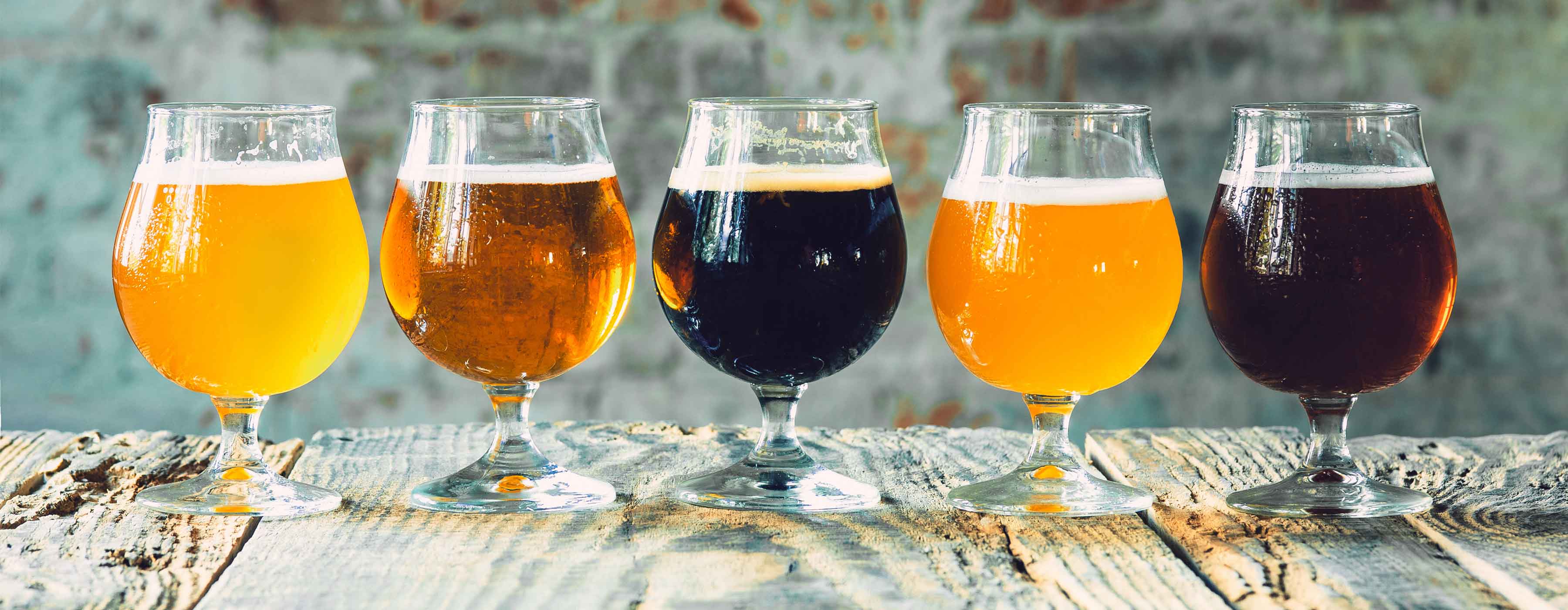 Básico em Cervejas: degustação, harmonização e serviço. Foto de vários copos de cerveja alinhados em cima de uma mesa. 
