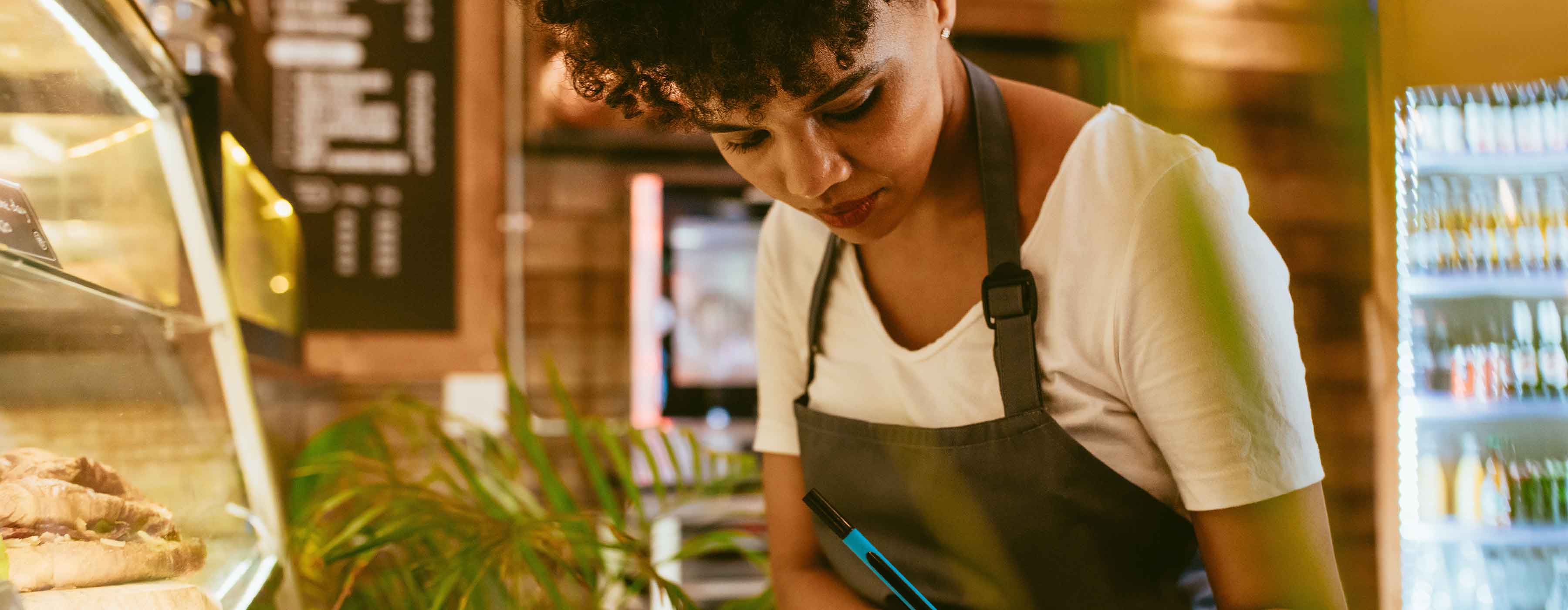 Bares e Restaurantes - planejamento. Foto de atendente fazendo anotações dentro de um restaurante.