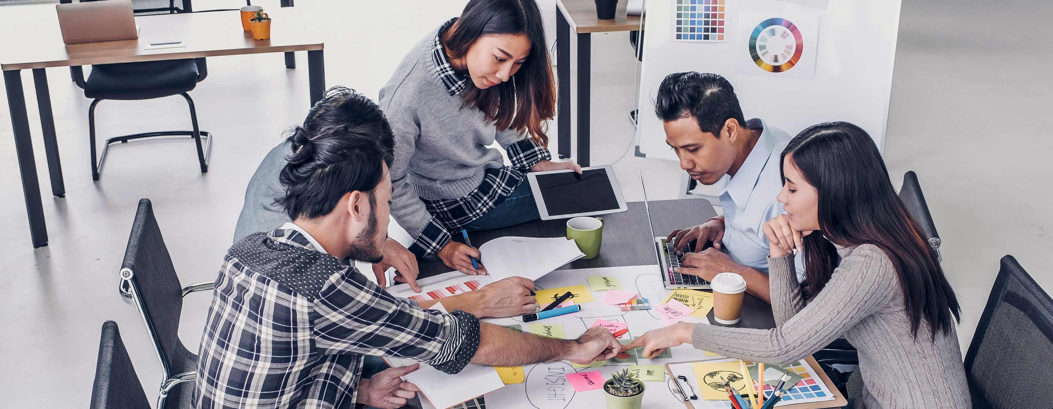 Storytelling: as narrativas no universo das marcas - foto de um grupo de jovens reunidos em uma sala criativa verificando diversos gráficos com estratégias e planos de comunicação.