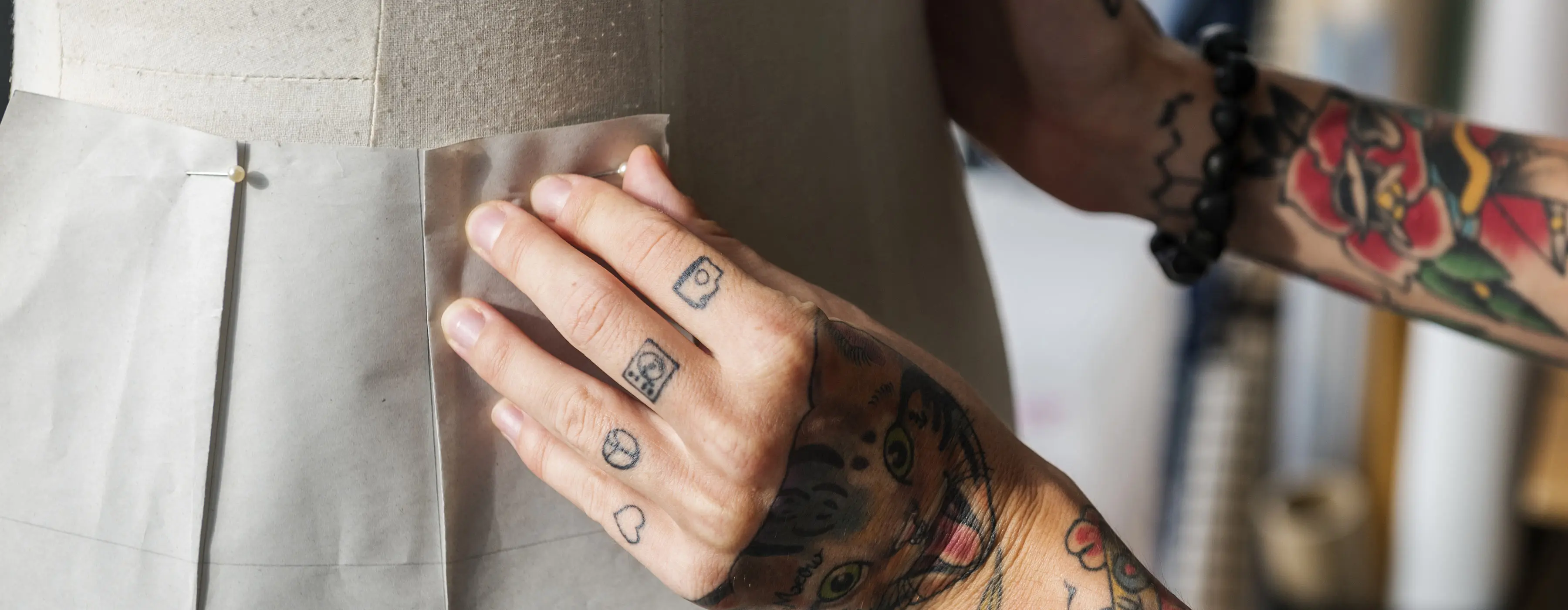 Foto em close das mãos de uma pessoa arrumando um croqui de modelagem em um manequim