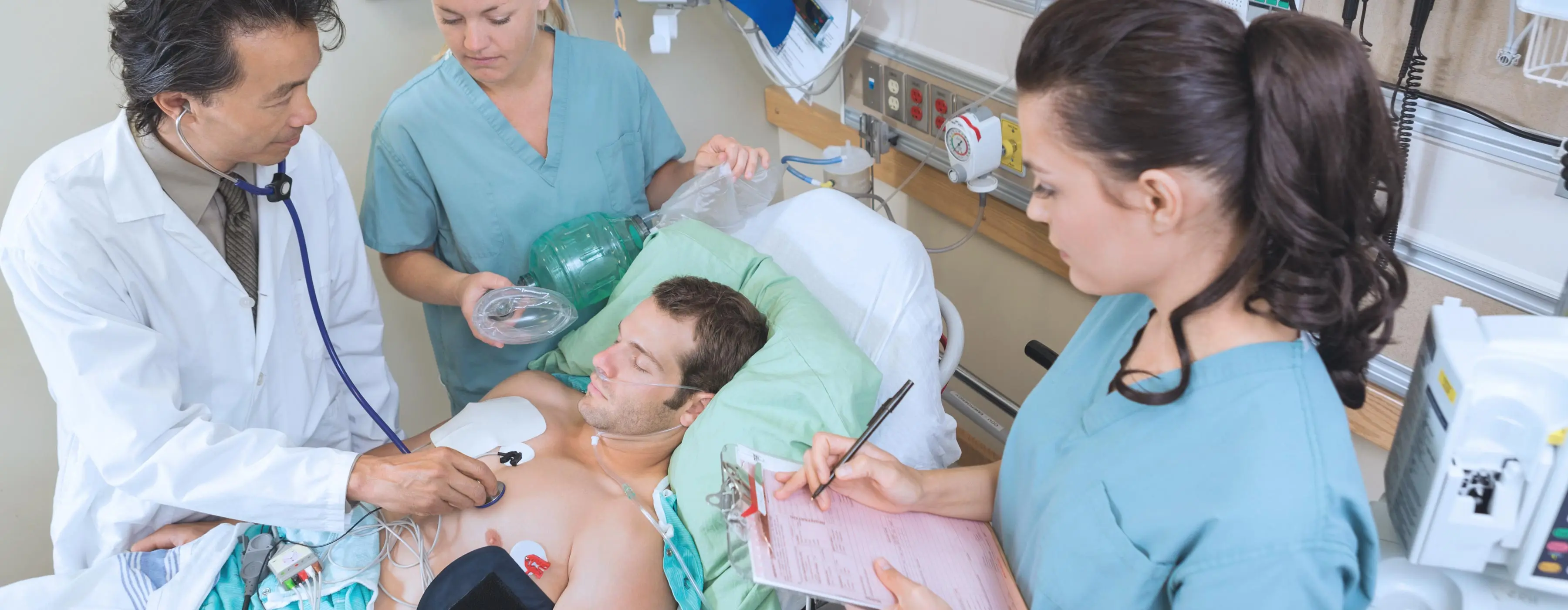 Foto de profissionais de saúde atendendo paciente entubado em hospital.