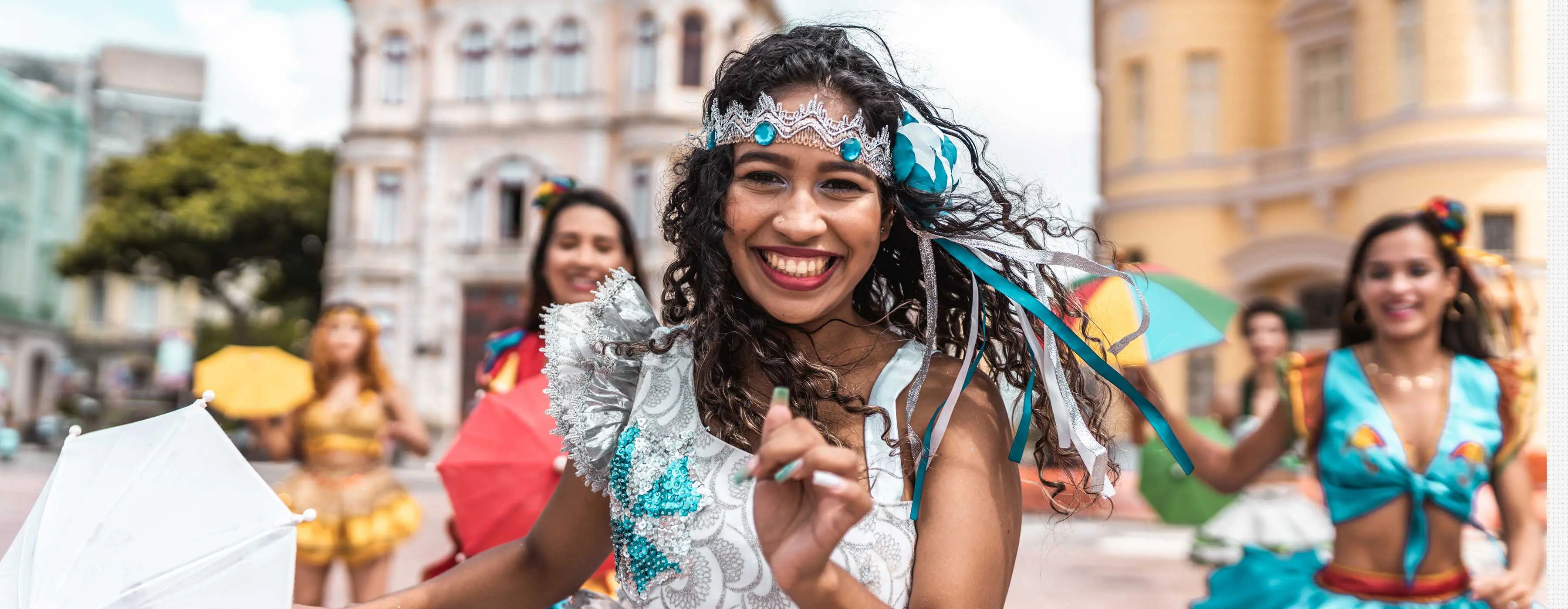 Foto de jovem dançarina de frevo sorrindo em apresentação de rua.