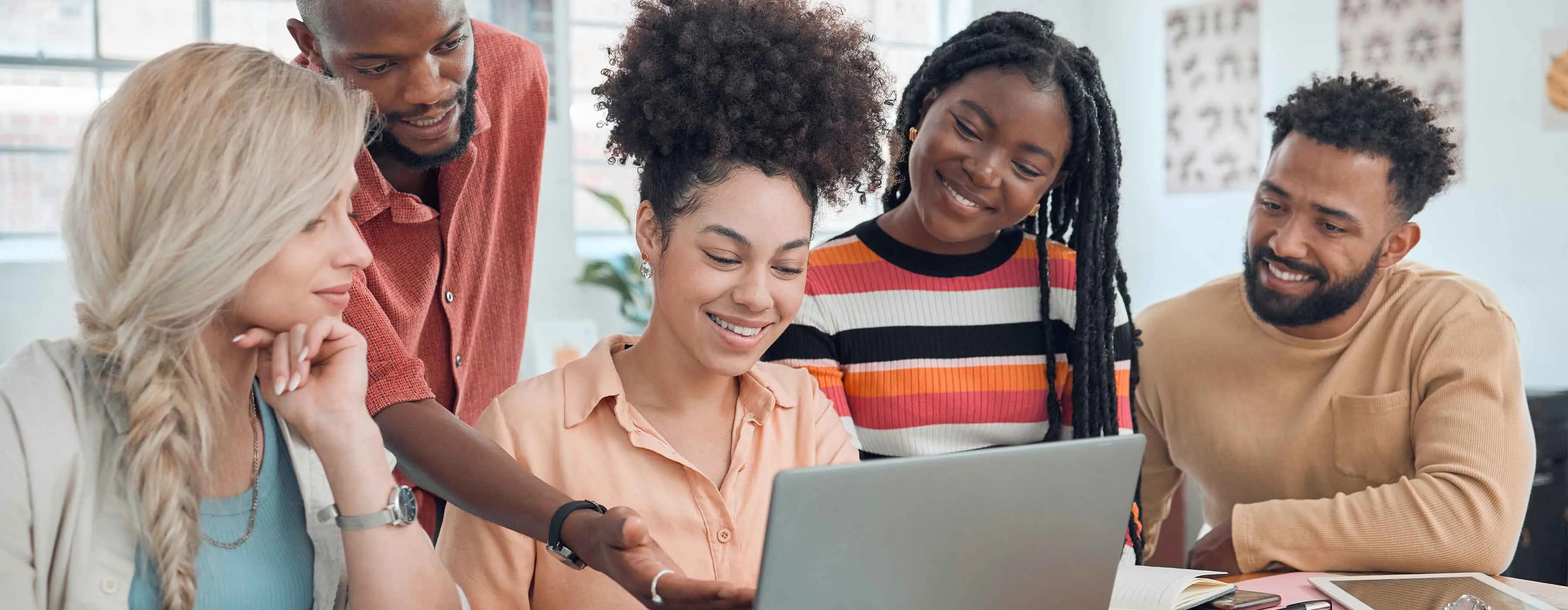 Grupo de homens e mulheres discutem dados apresentados em tela de notebook.
