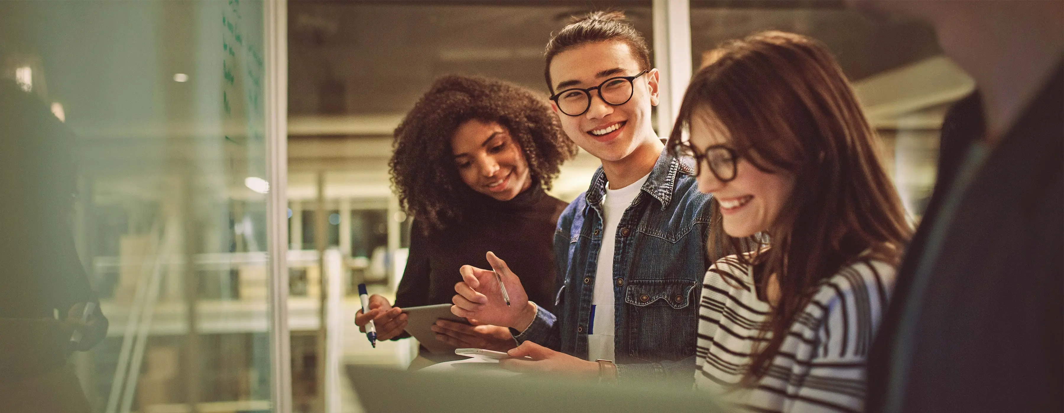 Foto de quatro jovens conversando em frente ao quadro branco.